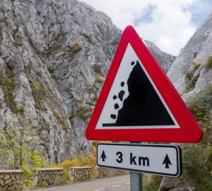Pictured: a sign on a mountain warning people that falling rocks may happen. The image is a metaphor for the pitfalls that can arise in brand assimilation.