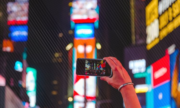 hand holding Iphone taking a picture of time square