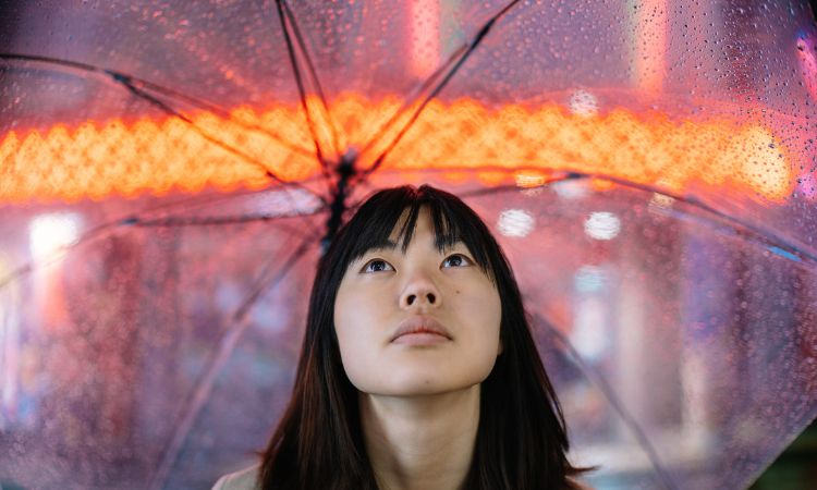 Woman Looking up in the rain holding an umbrella